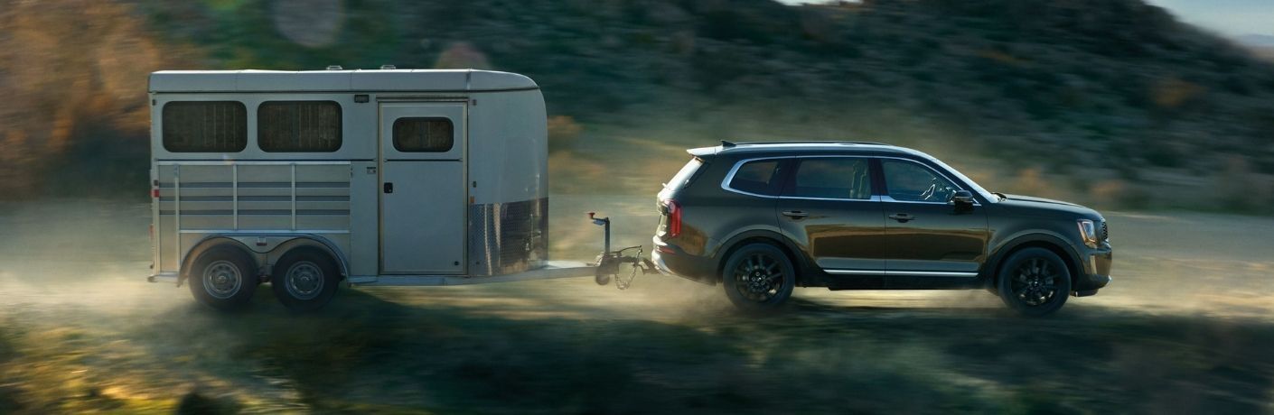 Exterior view of a green 2021 Kia Telluride towing a trailer