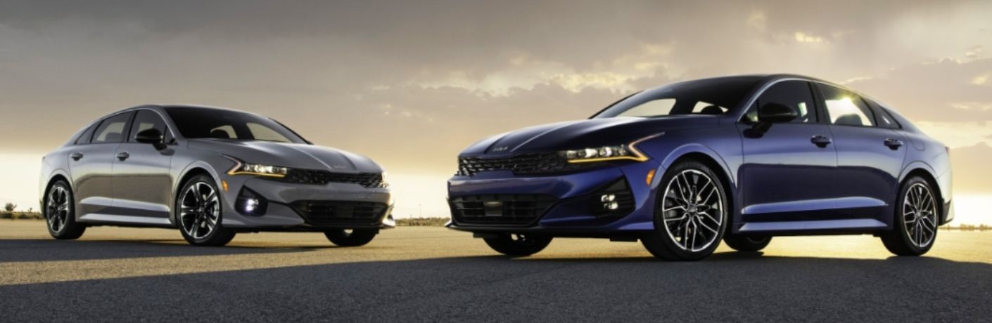 Two different 2023 Kia K5 models on a smooth road