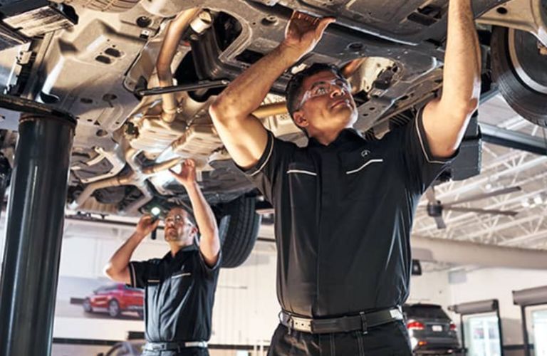 two Mercedes-Benz technicians working under the hood of a Mercedes-Benz