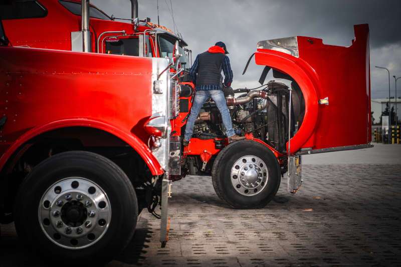 A man performing service on a commercial truck engine