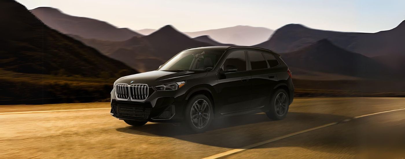 Black 2024 BMW X1 driving on a winding mountain road