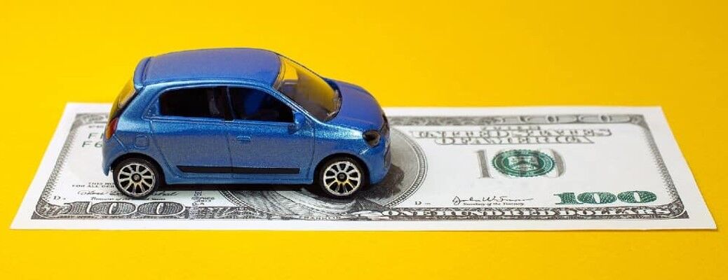 A blue vehicle driving on a one hundred dollar bill on a yellow background