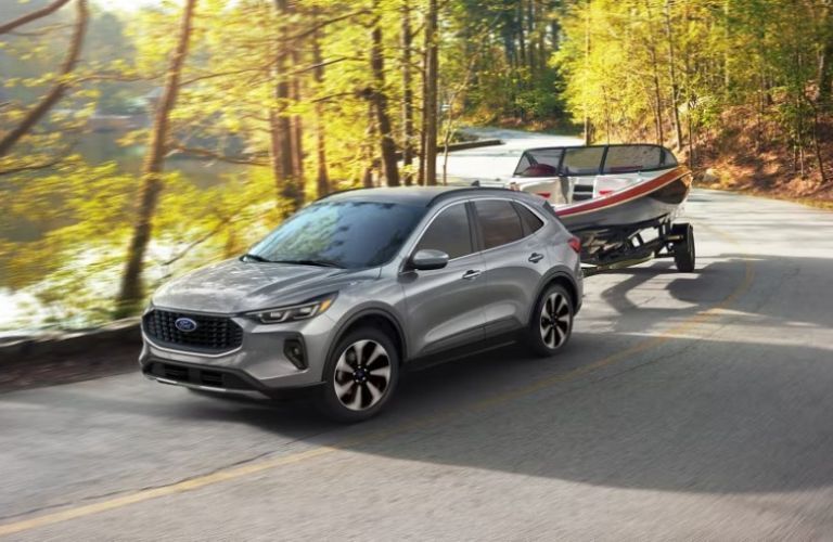 2024 Ford Escape towing a boat on a forest road