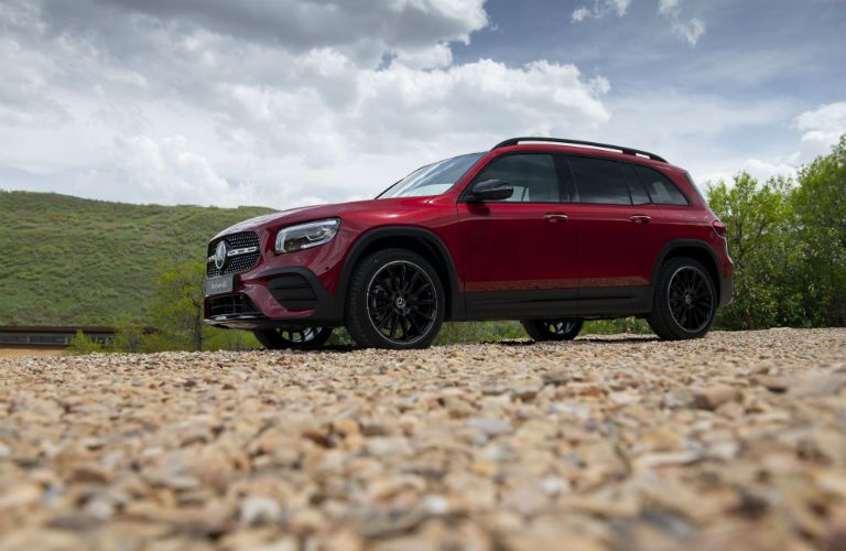 2020 MB GLB exterior front fascia and drivers side parked on gravel with grassy hill and trees behind it