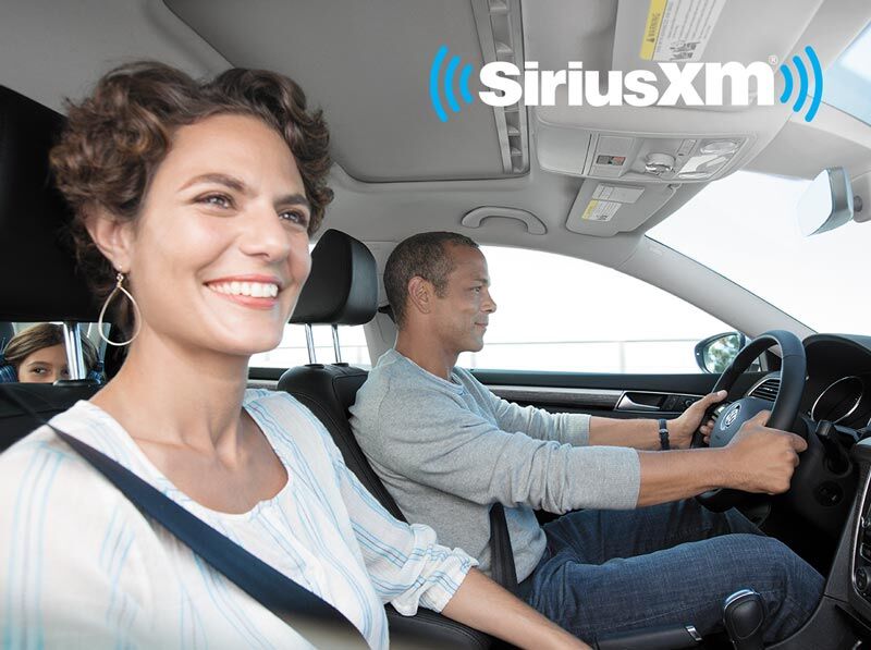 smiling couple in vehicle listening to SiriusXM