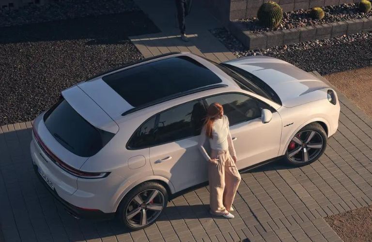 A lady leaning on the 2024 Porsche Cayenne Turbo E-Hybrid SUV