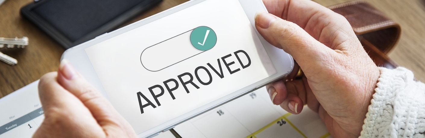 A woman holding a smartphone showing approved text