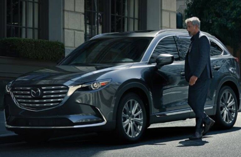 Front driver angle of a grey 2021 Mazda CX-9 with a man standing by it