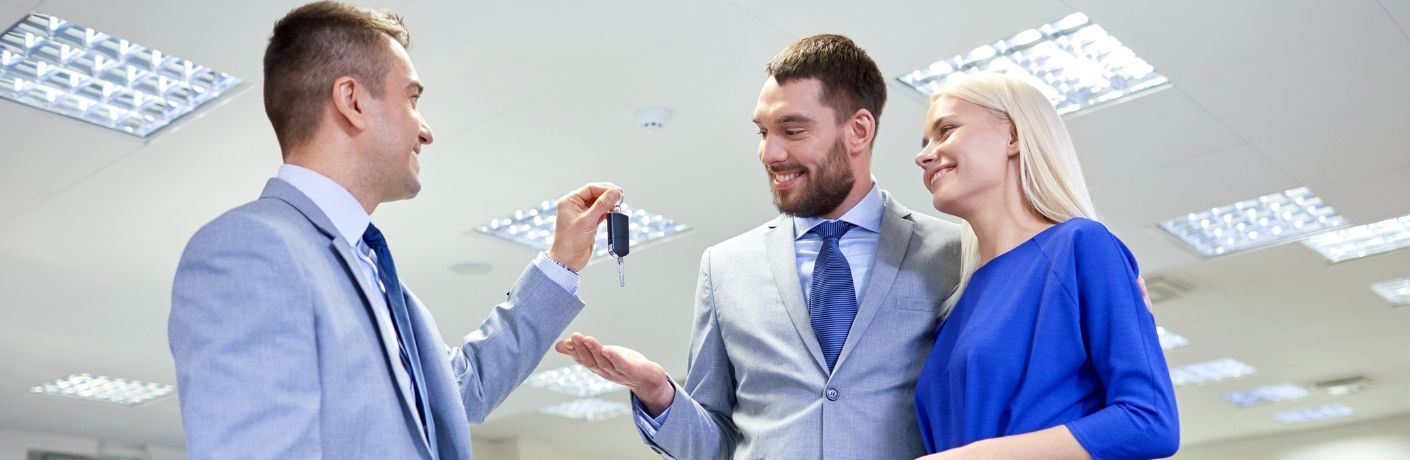 A salesman handing over car keys to a couple