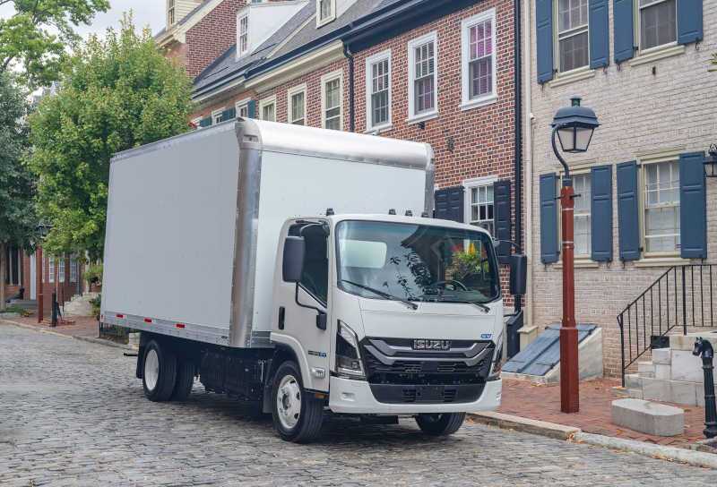 An Isuzu commercial truck outside a row of homes