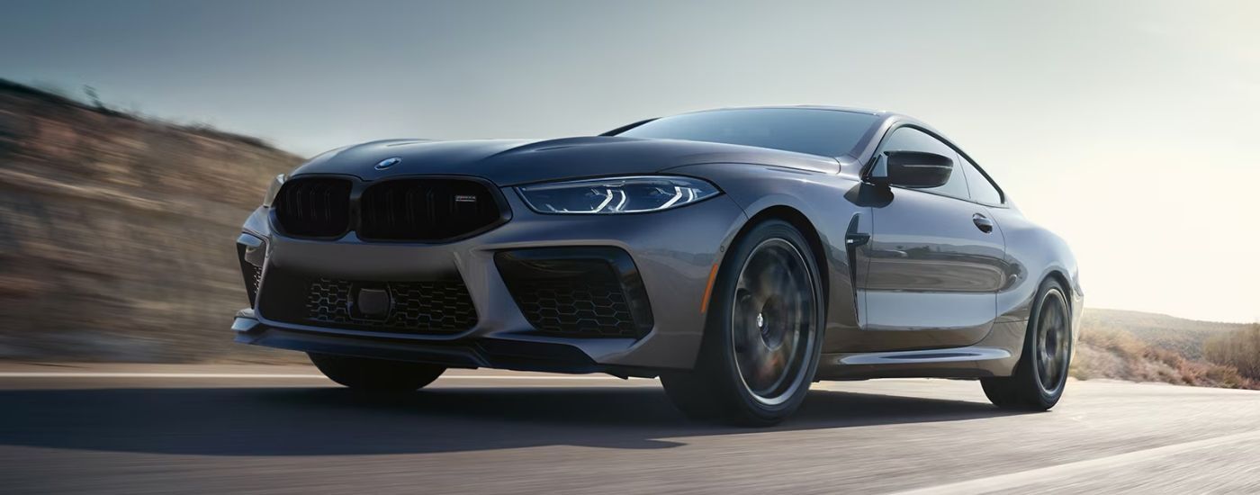 Silver 2025 BMW M8 Coupe driving to a BMW dealer