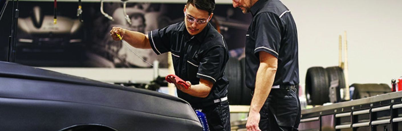 two technicians working under the hood of a Mercedes-Benz