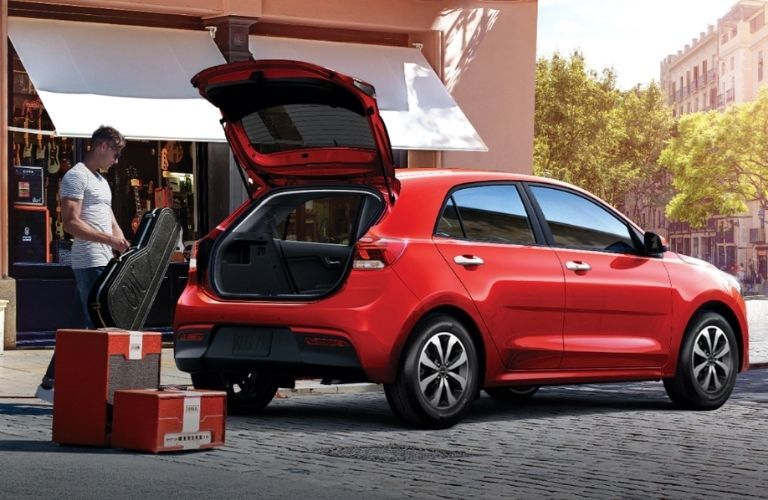 A person loading the Rio's trunk with large items
