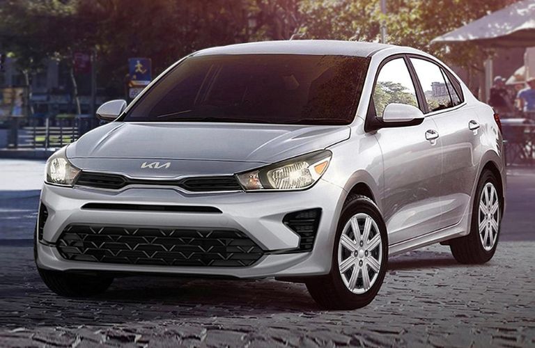One grey color 2023 Kia Rio is parked on the road in front of a shop.