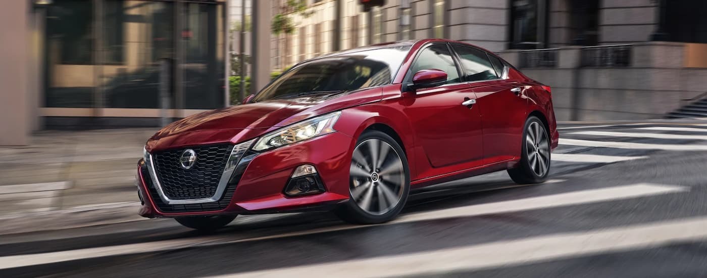 A red 2022 Nissan Altima driving on a city street after viewing cars for sale near North Bergen.