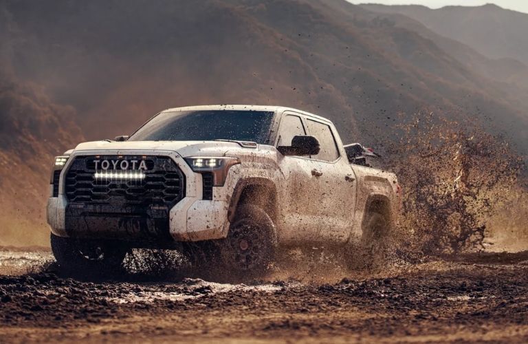 A 2024 Toyota Tundra spalshing through a muddy puddle