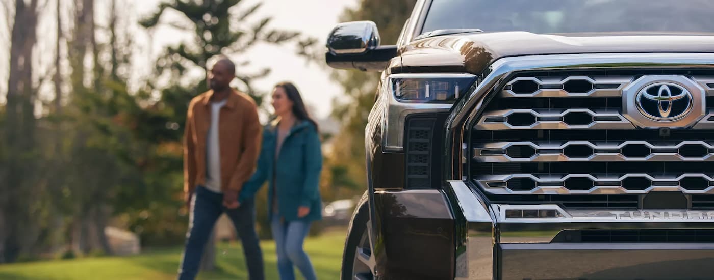 A couple walking behind a parked black 2022 Toyota Tundra 1794 CrewMax.