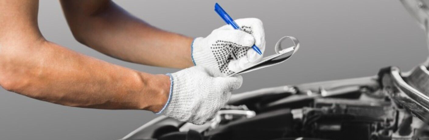 two gloved hands holding a clipboard and a blue pen