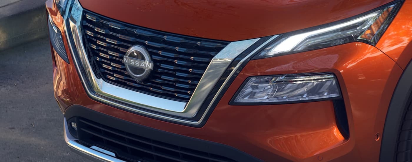 A close up of the grille and front of an orange 2023 Nissan Rogue at a used car dealership near North Bergen.