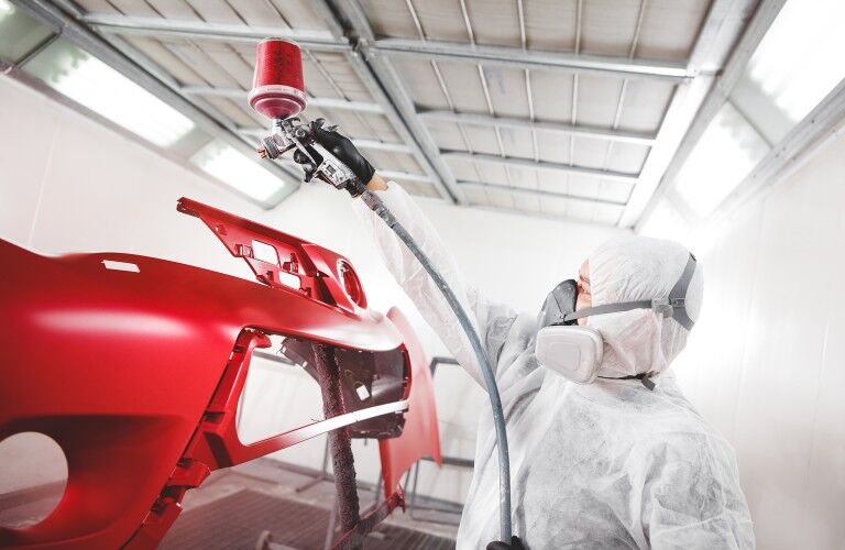 Mechanic painting a vehicle part red