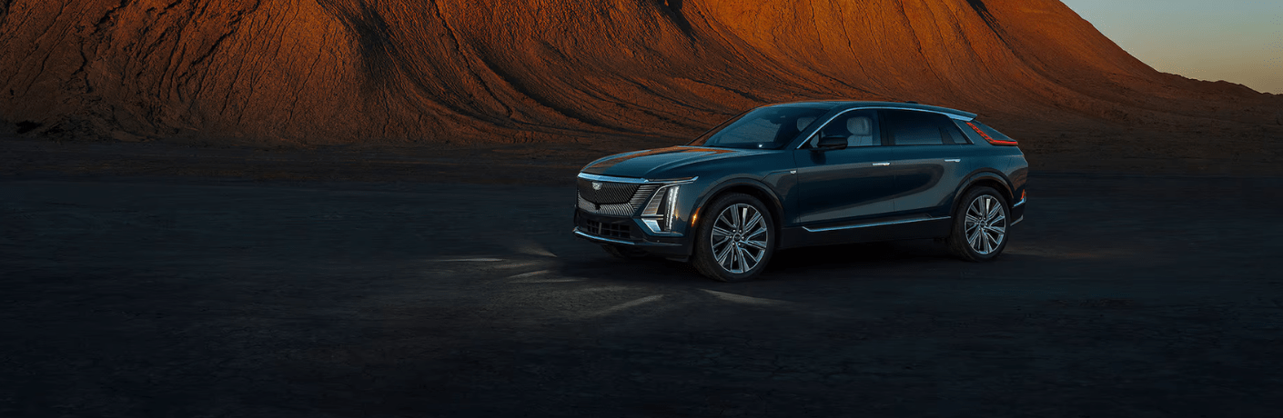 Side view of the 2024 Cadillac LYRIQ parked in a scenic desert landscape at sunset