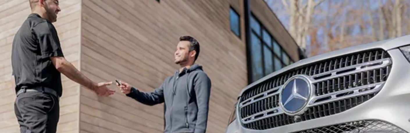 a person handing Mercedes-Benz car key to technician