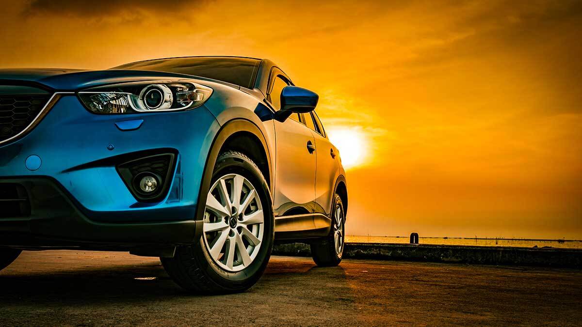 Car parked in an open field sunset in the background