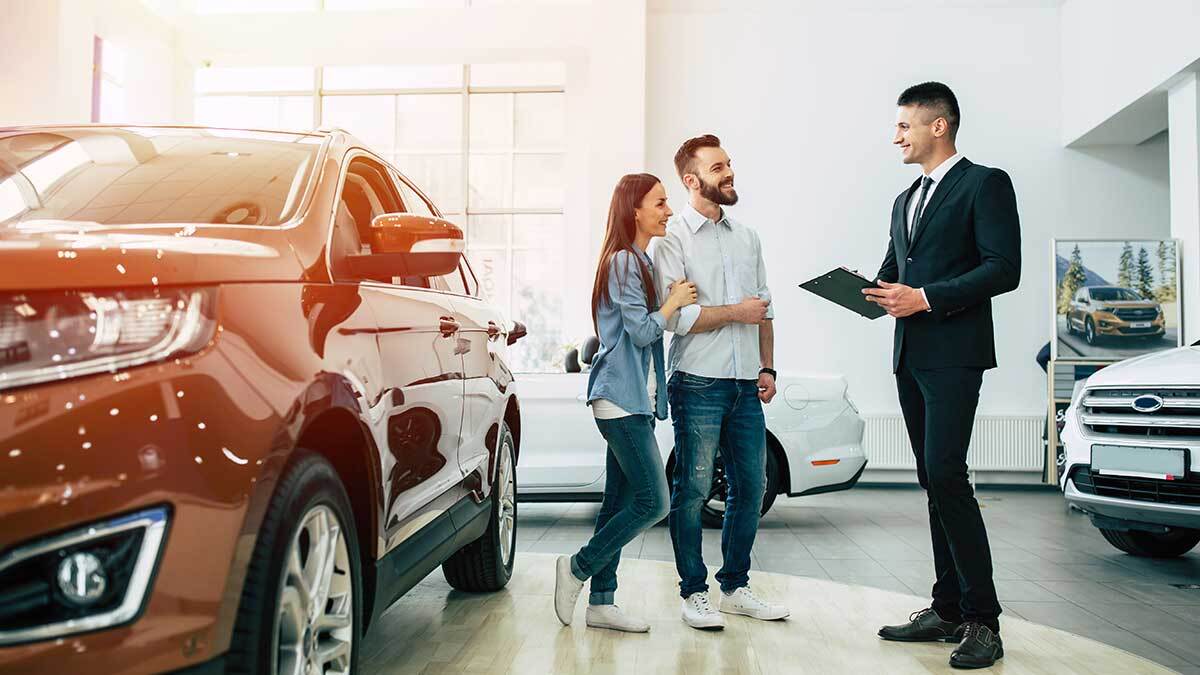 Couple standing by car talking with car salesman