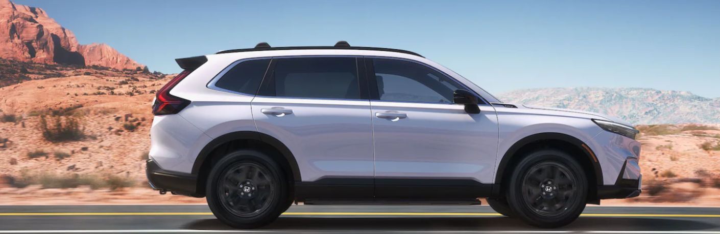 One white color 2023 Honda CR-V Hybrid car is running on the road.