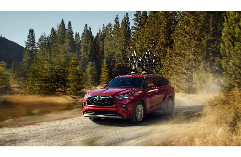 2021 Toyota Highlander exterior red driving through trees and path
