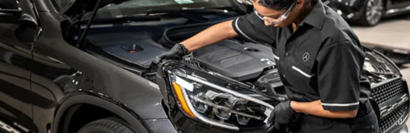 a technician working on the headlight of a Mercedes-Benz