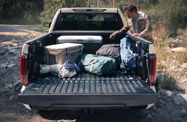 man putting luggage in the cargo bed of the 2025 Toyota Tundra
