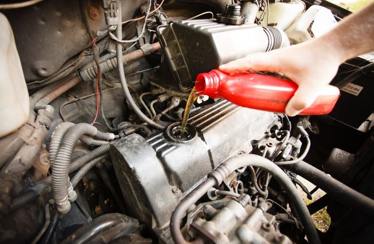 technician pouring oil in the car