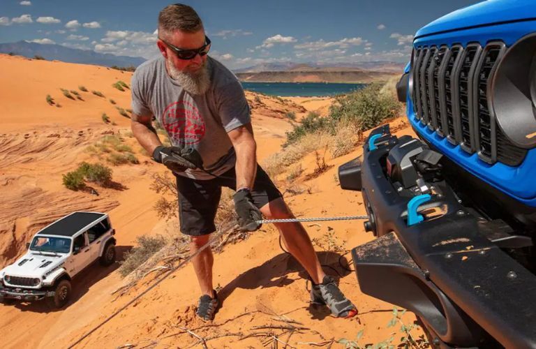 a driver attaching a rope onto a 2025 Jeep Wrangler