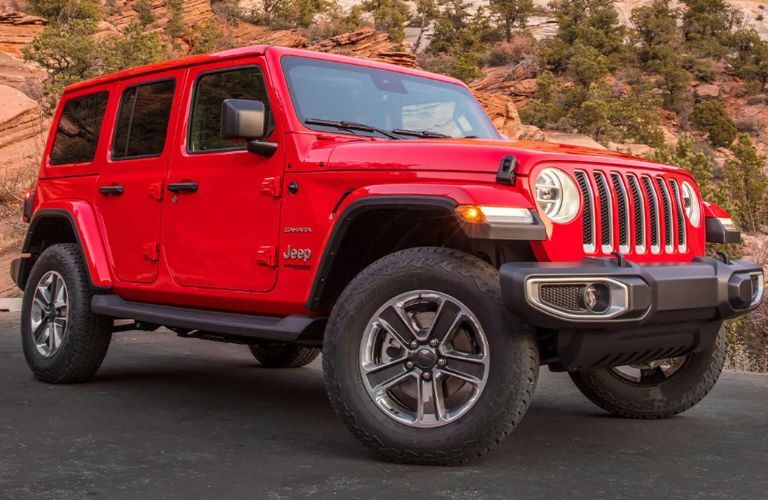 One red color 2022 Jeep Wrangler is parked on the road surrounded by the hill.