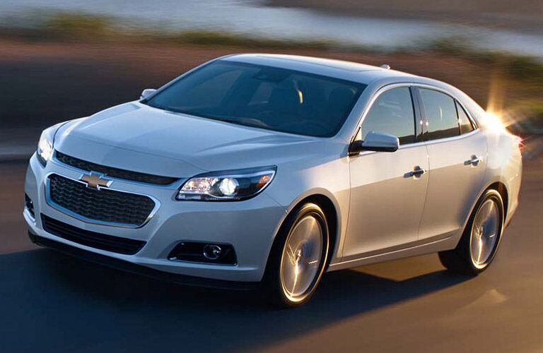 Front driver angle of a white 2014 Chevrolet Malibu driving on a road