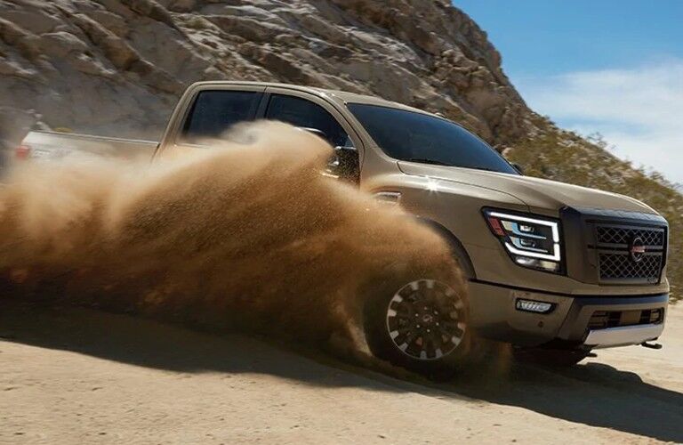 Front passenger angle of a tan 2020 Nissan TITAN driving in sand