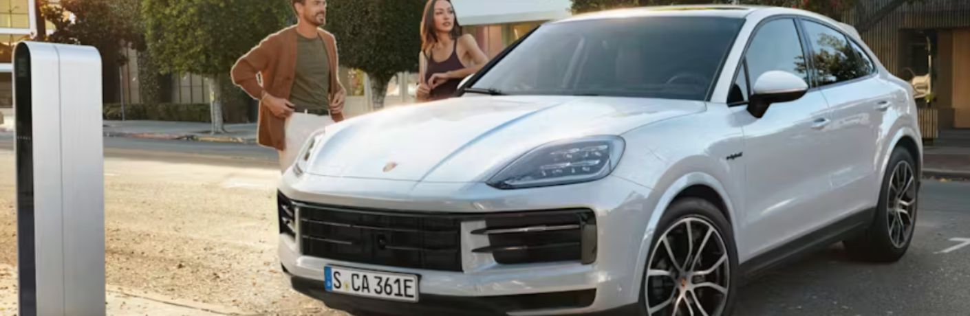 two people standing next to a 2026 Porsche Cayenne Coupe