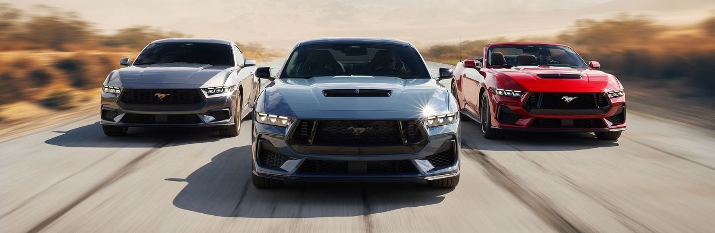 Front view of three 2024 Ford Mustang driving on the road