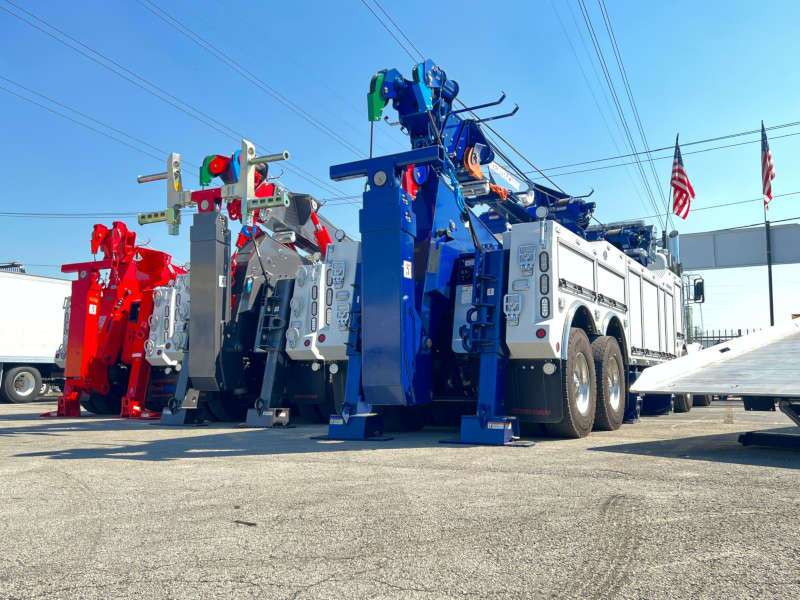A rear quarter exterior view of a several heavy duty tow trucks