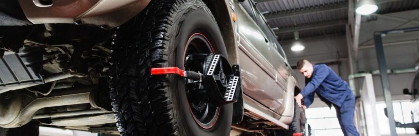 One mechanic is working on a car tire in a garage.