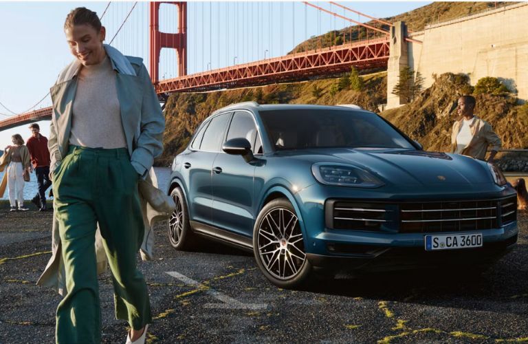 a woman smiling and walking away from the 2026 Porsche Cayenne
