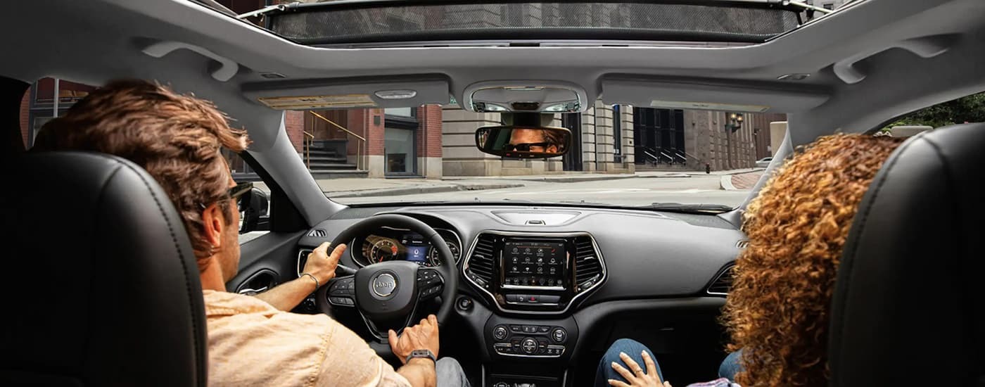 Two people driving in a 2023 Jeep Cherokee Altitude.