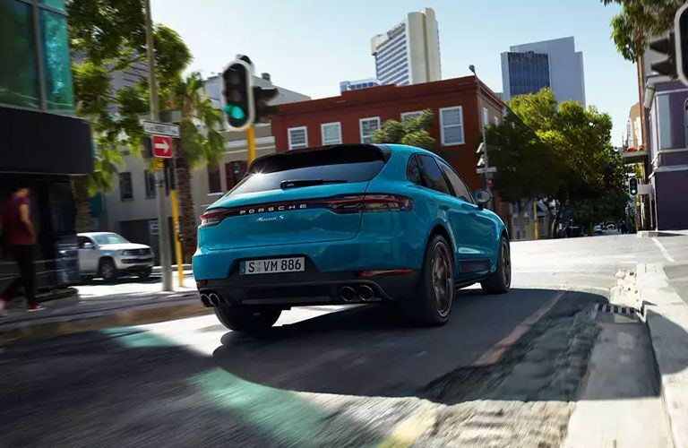 Rear image of a Blue 2021 Porsche Macan driving through the city.