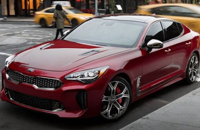 A red-colored 2021 Kia Stinger parked on the side of a road in the city