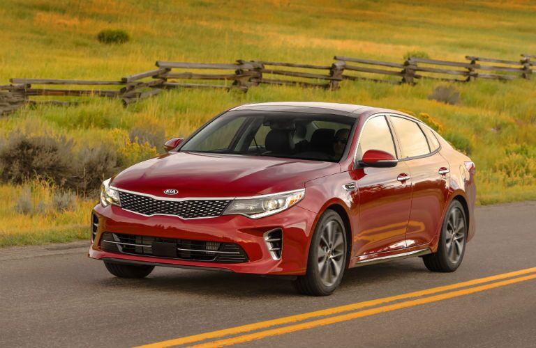 Red 2018 Kia Optima cruising through the road