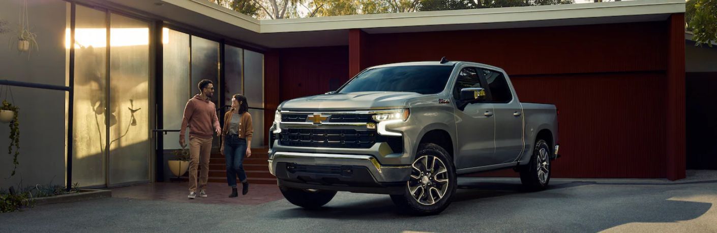 2023 Chevrolet Silverado parked outside a house with a couple in he background