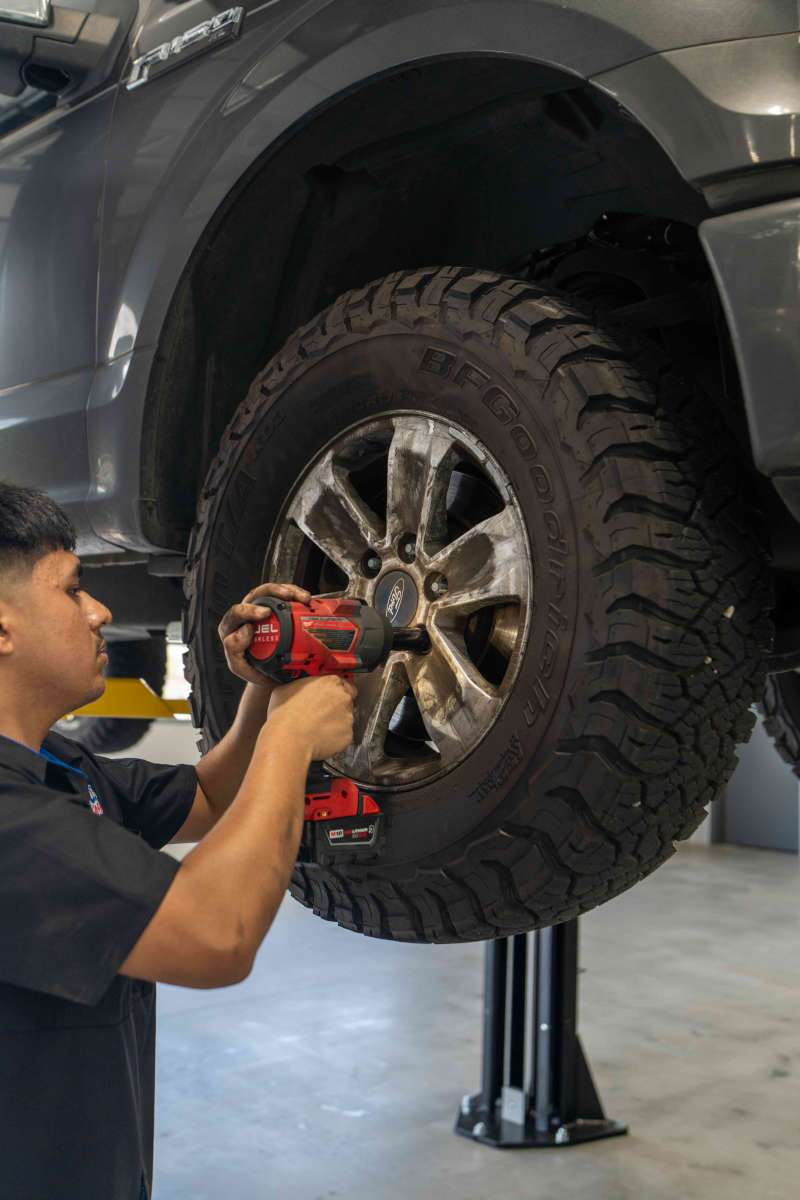 A Wild Willies technician replacing a heavy duty offroad tire on a custom pickup truck