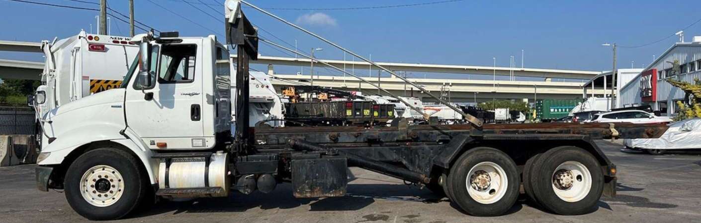 A side view of a used roll off truck for sale at Dirt Cheap Truck Sales in Tampa, FL.