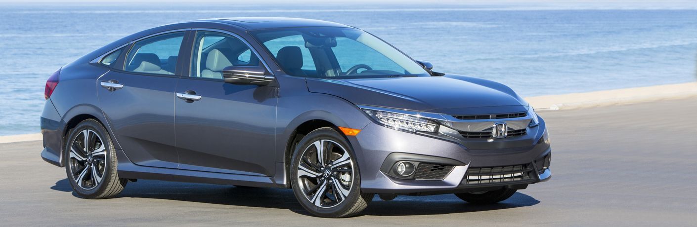 Exterior view of a gray 2018 Honda Civic parked near a beach with water in background